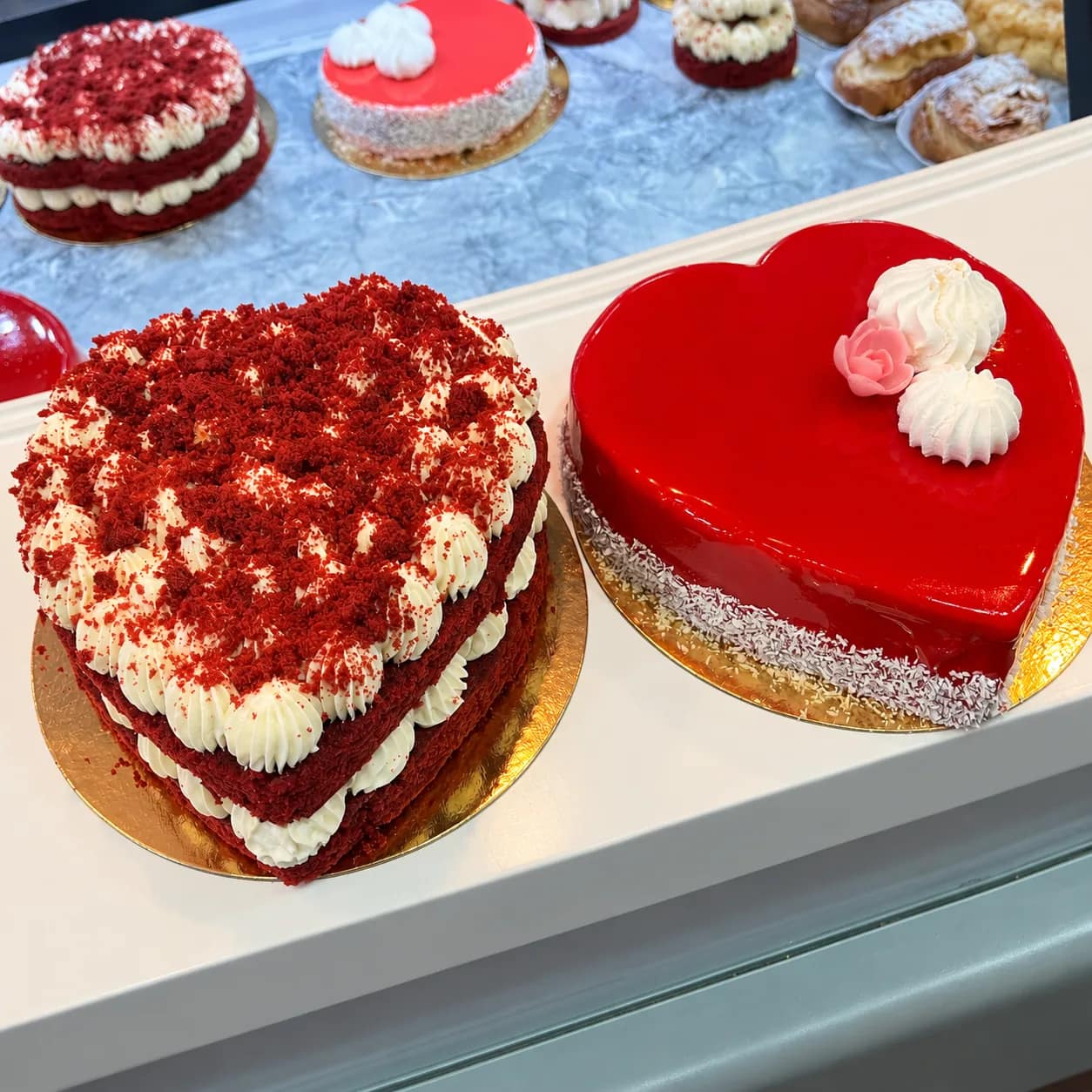Deux gâteaux en forme de cœur : un red velvet à la crème et un entremets au glaçage rouge